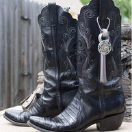 Pair of worn black cowboy boots with a decorative keychain.