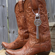 Pair of intricately designed brown leather cowboy boots with a keychain attached.
