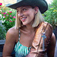 Woman in hat holding cowboy boot.
