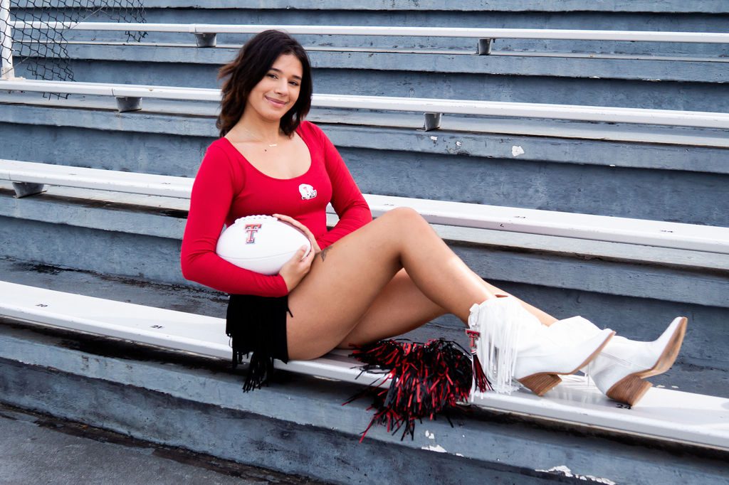 Cheerleader sitting on bleachers with football.