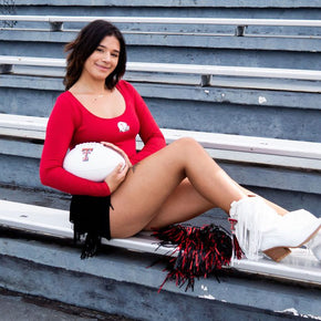 Cheerleader sitting on bleachers with football.
