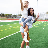 Two cheerleaders posing on a football field.