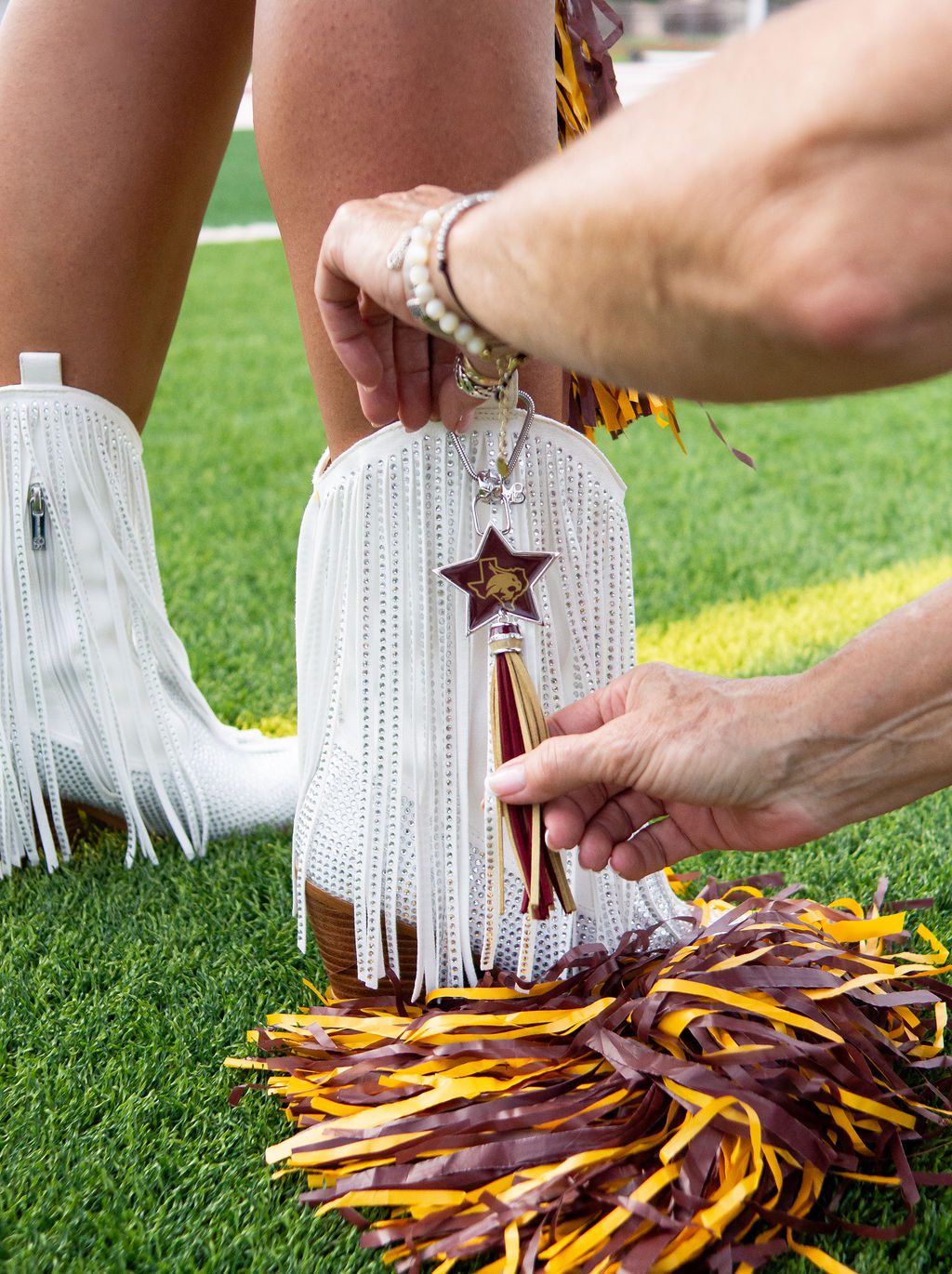 Attaching charm to white fringe boots.