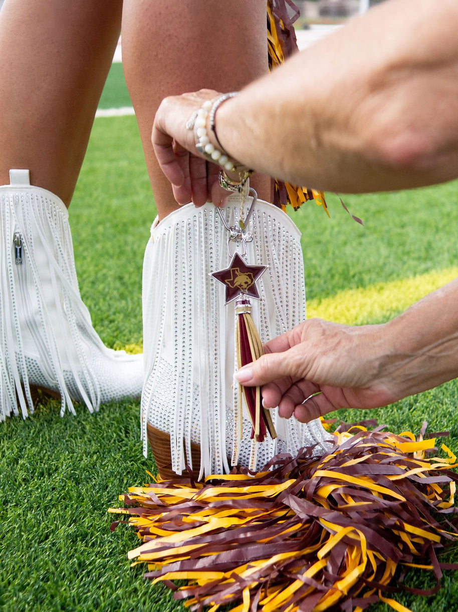 Attaching charm to white fringe boots.