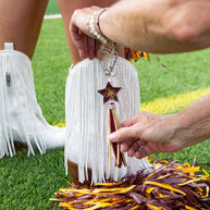 Attaching charm to white fringe boots.