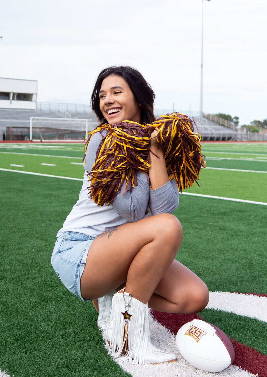 Cheerleader kneeling on football field, smiling.